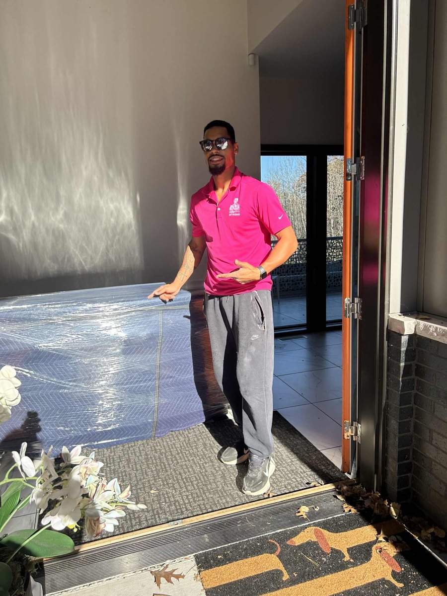 Ty from the Pretty Strong Movers crew, in a pink Pretty Strong polo at a customer's home
